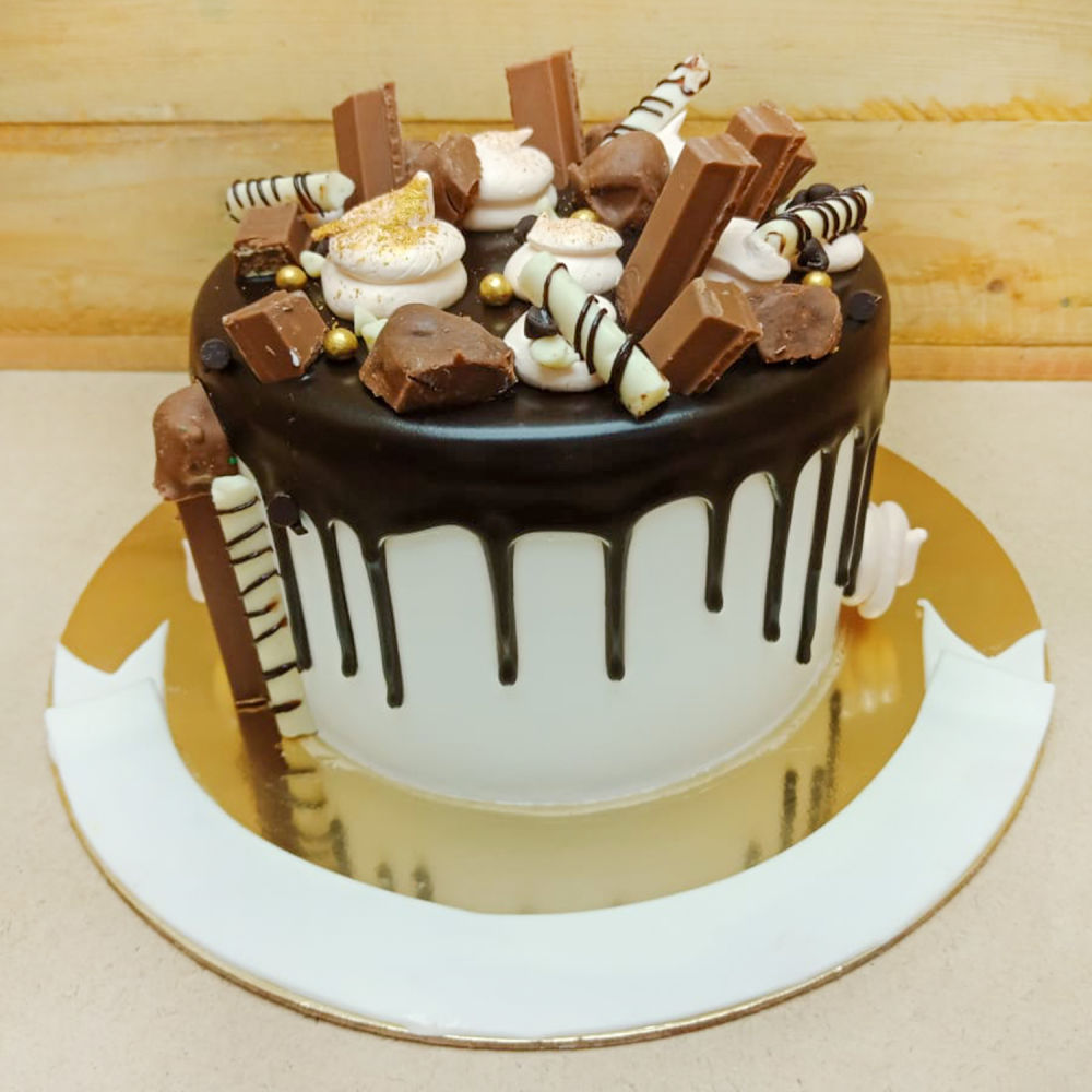 White chocolate drip cake with sprinkles and mini choco bars - FunCakes